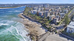 Una zona residencial costera con propiedades frente a la playa, incluyendo edificios de varios pisos y una playa arenosa.