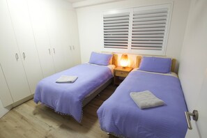 Una camera da letto con due letti, un armadio e una finestra con persiane.