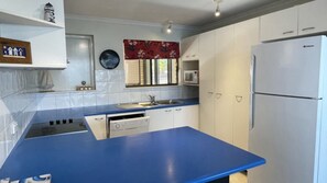 Une cuisine avec un plan de travail bleu, des armoires blanches, un four à micro-ondes et un réfrigérateur.