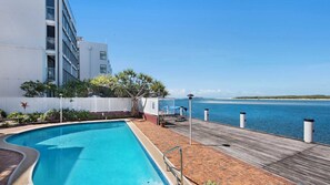 Une piscine avec une terrasse en bois et vue sur la mer.