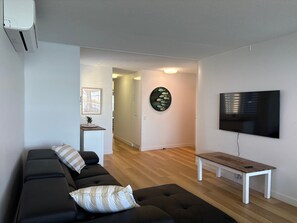 Un salon moderne avec un canapé d’angle, un téléviseur à écran plat et un banc en bois.