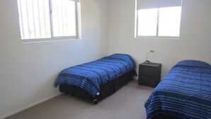Une chambre avec deux lits, une table de chevet et une fenêtre.