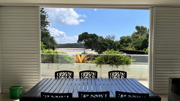 Un balcon avec une table et des chaises, une vue sur la plage et quelques plantes.