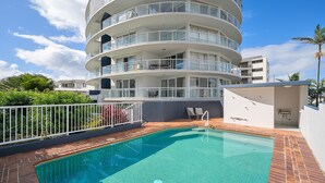 A multi-story residential building with a swimming pool and outdoor seating area.