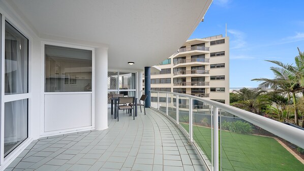 Un balcon donnant sur un immeuble et une pelouse verdoyante.