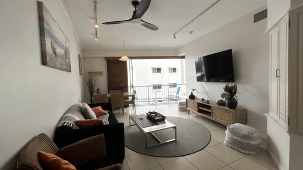 A modern living room with a sofa, coffee table, and a flat-screen TV mounted on the wall.