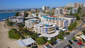 A coastal hotel with multiple buildings, a beach, and a parking area.