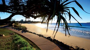 A coastal walkway with a view of the ocean and a city skyline in the distance.