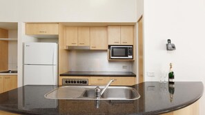 A kitchen with a built-in microwave, a stainless steel sink, and wooden cabinets.