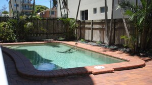Una piscina rectangular con un deck de madera alrededor.