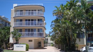 Un hotel de varios pisos con balcones, palmeras y cielo despejado.