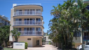 A multi-story hotel with balconies, palm trees, and a clear sky. - Summervale - Central Caloundra Apt, Pool & Beach (Caloundra)