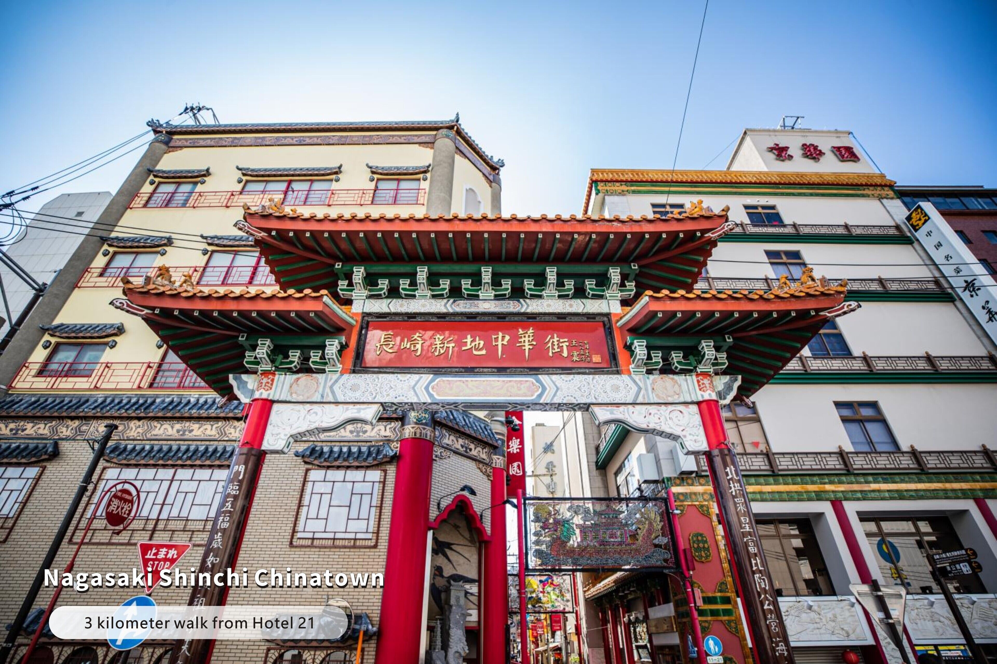 A traditional Chinese gate with intricate designs and a red roof, leading to a street lined with buildings.