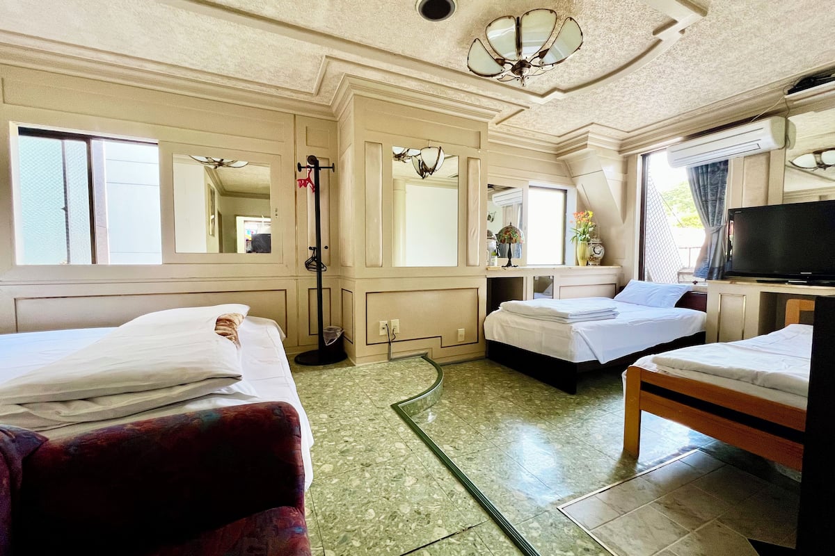 A hotel room with two beds, a desk, a television, and a window.