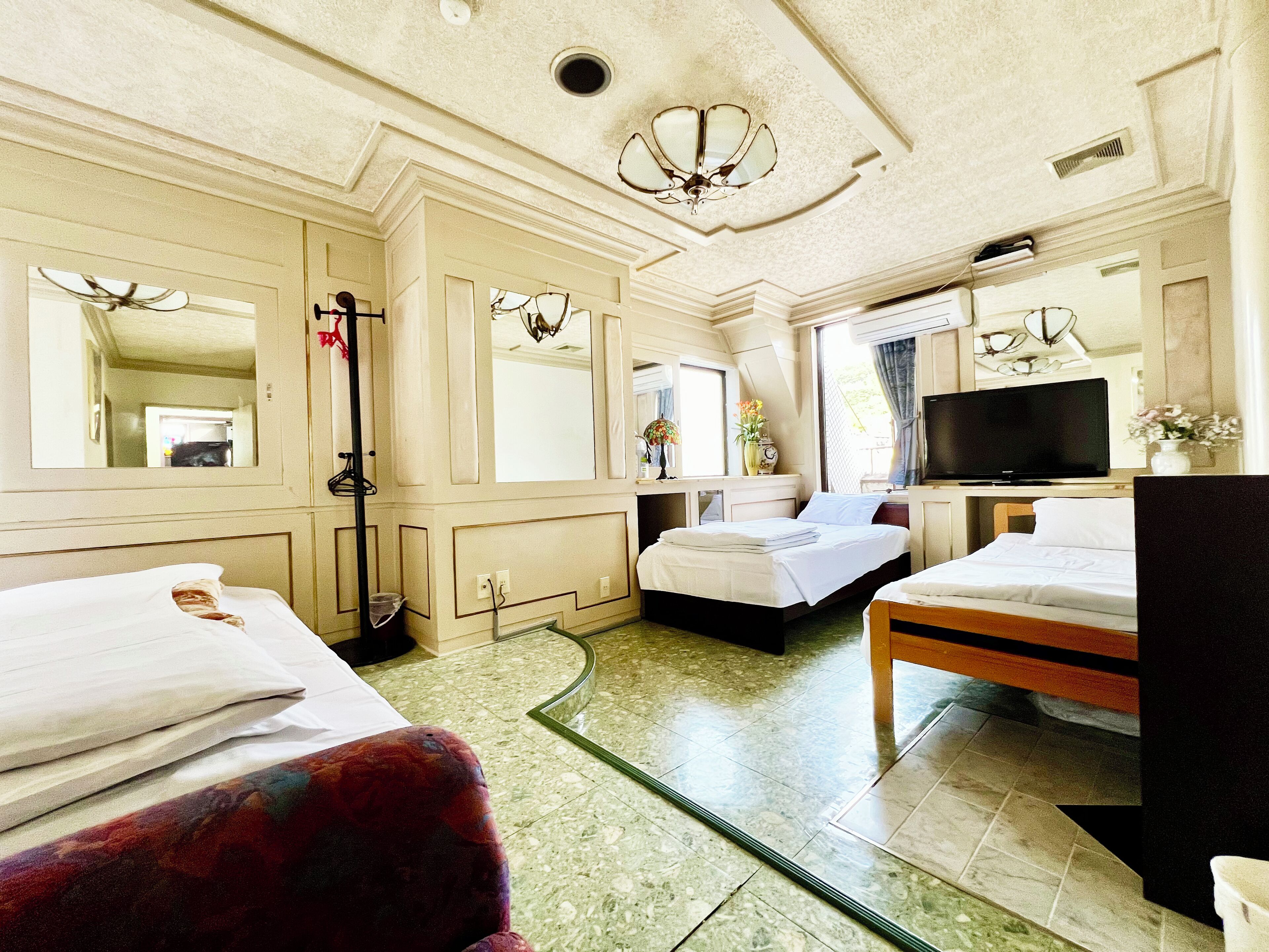 Habitación de hotel con dos camas, televisión, espejo y ventana.