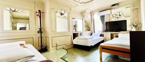 Habitación de hotel con dos camas, televisión, espejo y ventana.
