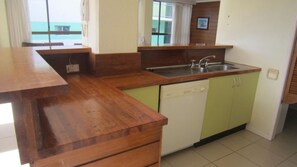 A kitchen with wooden countertops, a sink, and green cabinets.