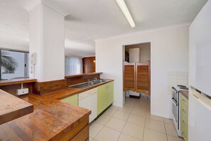 Une cuisine compacte dotée d’un plan de travail en bois, d’un lave-vaisselle encastré et d’une cuisinière.