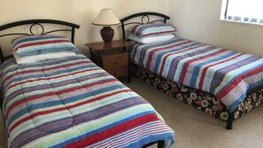 Two single beds with striped bedding, a nightstand with a lamp, and a window with blinds. - Sahara Sands U4-Kings Beach Escape (Kings Beach)
