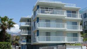 A multi-story residential building with balconies, a brick facade, and a clear sky. - Spinnaker Seas Walk To Kings Beach | Ocean Views | Pool (Kings Beach)