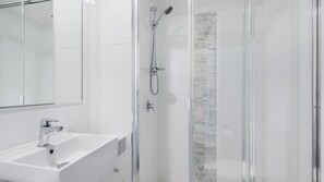 A modern bathroom with a glass shower enclosure, a sink, and a mirror. - Centrepoint 27 | Ocean Views Walk To Bulcock Beach (Caloundra)