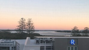 A building with a rooftop terrace overlooking a body of water and trees. - Centrepoint 27 | Ocean Views Walk To Bulcock Beach (Caloundra)