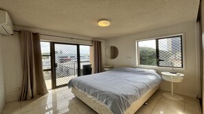 A hotel room with a bed, a bedside table, a round mirror, and a window with a view of the outside. - Balamara U3 Water Views, Walk to Bulcock Beach (Caloundra)