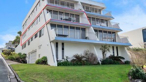 A multi-story building with a flat roof, balconies, and a well-maintained lawn. - Wickham Point - Kings Beach With Ocean Views (Kings Beach)