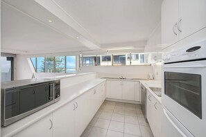 Una cocina moderna con armarios blancos, horno empotrado y ventana con vistas panorámicas.