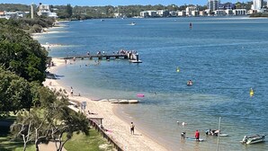A beach with a wooden pier, clear water, and a city skyline in the background. - Riviere 718 Stunning Panoramic Golden Beach Views (Golden Beach)