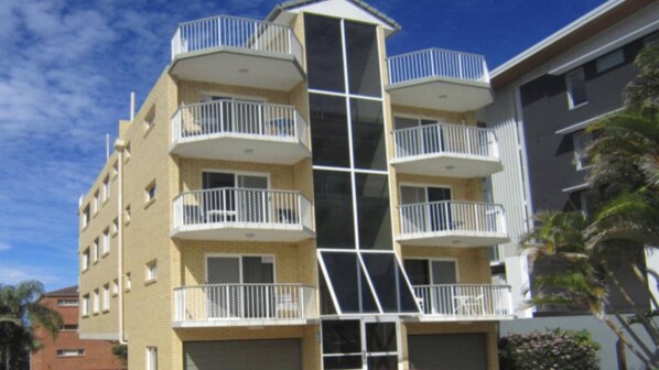 A multi-story building with balconies, a central glass elevator shaft, and a brick facade. - Solaris Court U2 Relax Swim and Unwind (Kings Beach)
