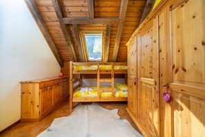 A room with a sloped ceiling, wooden bunk beds, a wardrobe, and a window. - GuestHost - Functional 60 sqm apartment, ideal for 6 guests, 3 min walk from the Italian Ski and Snowboard School Tarvisio - Sella Nevea. Tarvisio, located in the heart of the Julian Alps, offers breathtaking landscapes and a rich variety of hiking trail (Tarvisio)