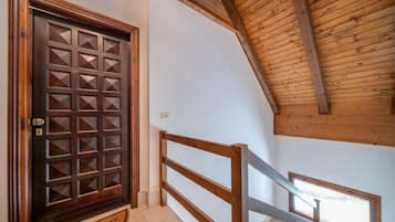 Una porta in legno con un motivo geometrico, una scala in legno con ringhiera e una finestra con vista.