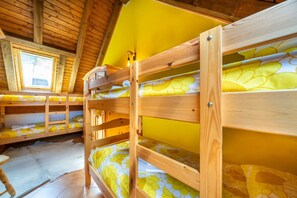 Une chambre avec des lits superposés, une lucarne et un mur jaune.