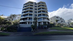 A multi-story residential building with a flat roof, balconies, and a gated entrance.