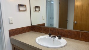 A bathroom with a white sink, a mirror, and a door. - Allamanda Place U5 Bulcock Beach Waterfront Views (Caloundra)