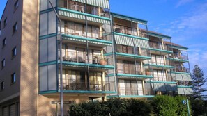 Un edificio de varios pisos con balcones, fachada de ladrillo y cielo despejado.
