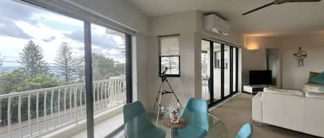 Una sala de estar moderna con balcón, ventilador de techo y televisor.
