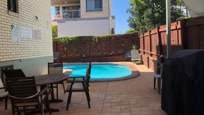 Un jardin avec une piscine, du mobilier de jardin et une clôture en bois.