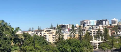 A cityscape with multi-story buildings, trees, and a clear sky.