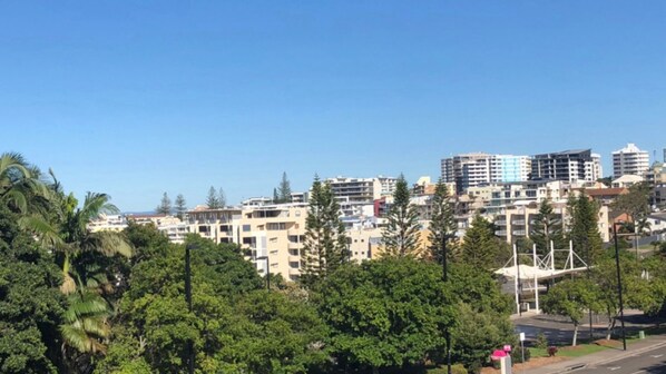 Un paysage urbain avec des immeubles à plusieurs étages, des arbres et un ciel dégagé.