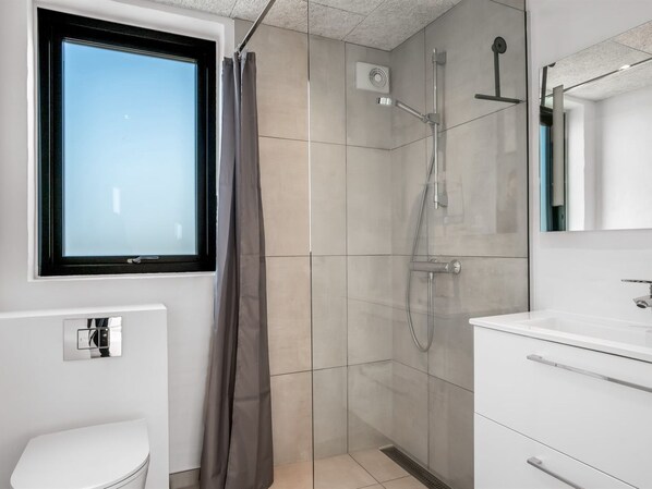 A modern bathroom with a shower, toilet, and sink.