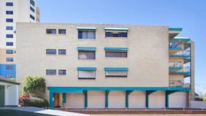 Un edificio de varios pisos con fachada plana, múltiples ventanas y un detalle azul en la parte inferior.