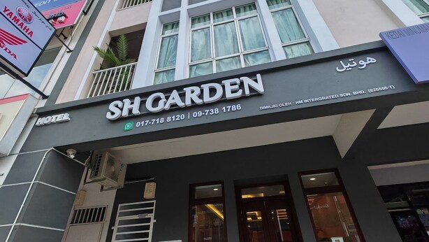A hotel named SHO GARDEN with a modern facade, large windows, and a signboard displaying contact information. - SH GARDEN HOTEL (Tanah Merah)
