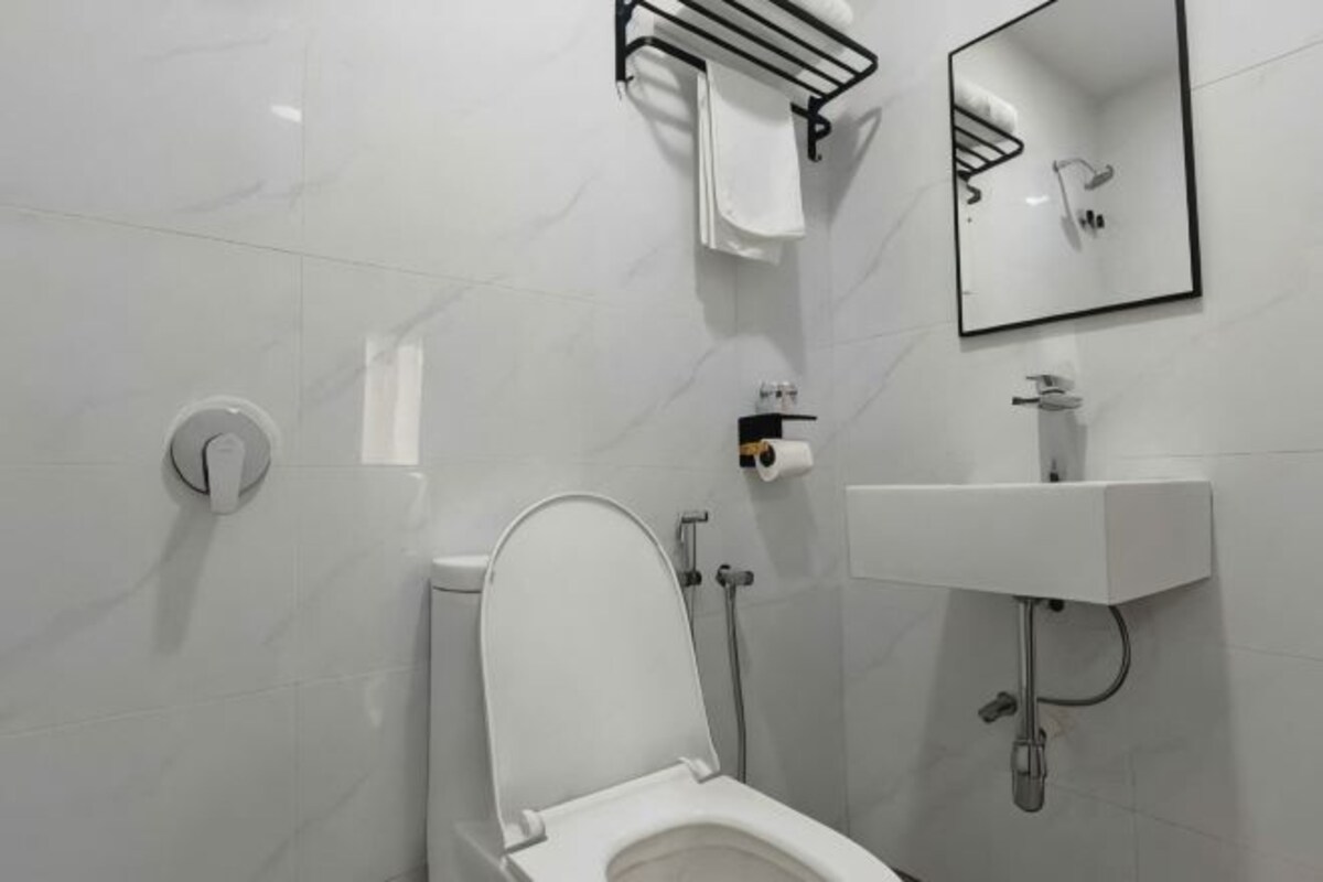 A modern bathroom with a toilet, sink, and mirror.