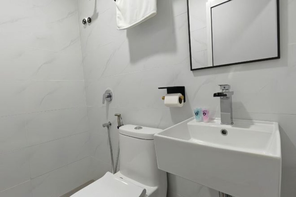 A modern bathroom with a toilet, sink, and mirror.