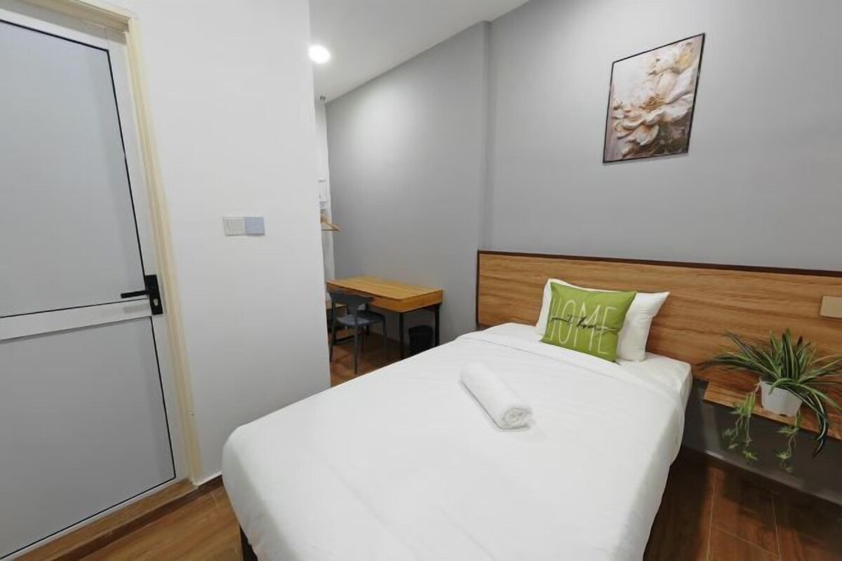 A hotel room with a bed, a desk, and a chair.