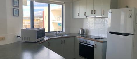 Eine moderne Küche mit Mikrowelle, Herd, Spüle und Kühlschrank.