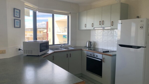 A modern kitchen with a microwave, stove, sink, and refrigerator.