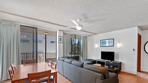A modern living room with a sofa, TV, dining table, and chairs.